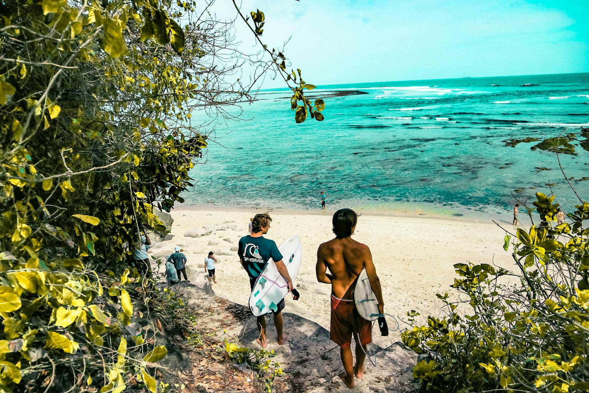two man holding surfboards going to beach